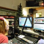 Radio Station DJ sat at mixing desk inside studio