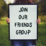 Join our Friends Group poster held up in a park