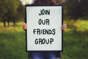 Join our Friends Group poster held up in a park